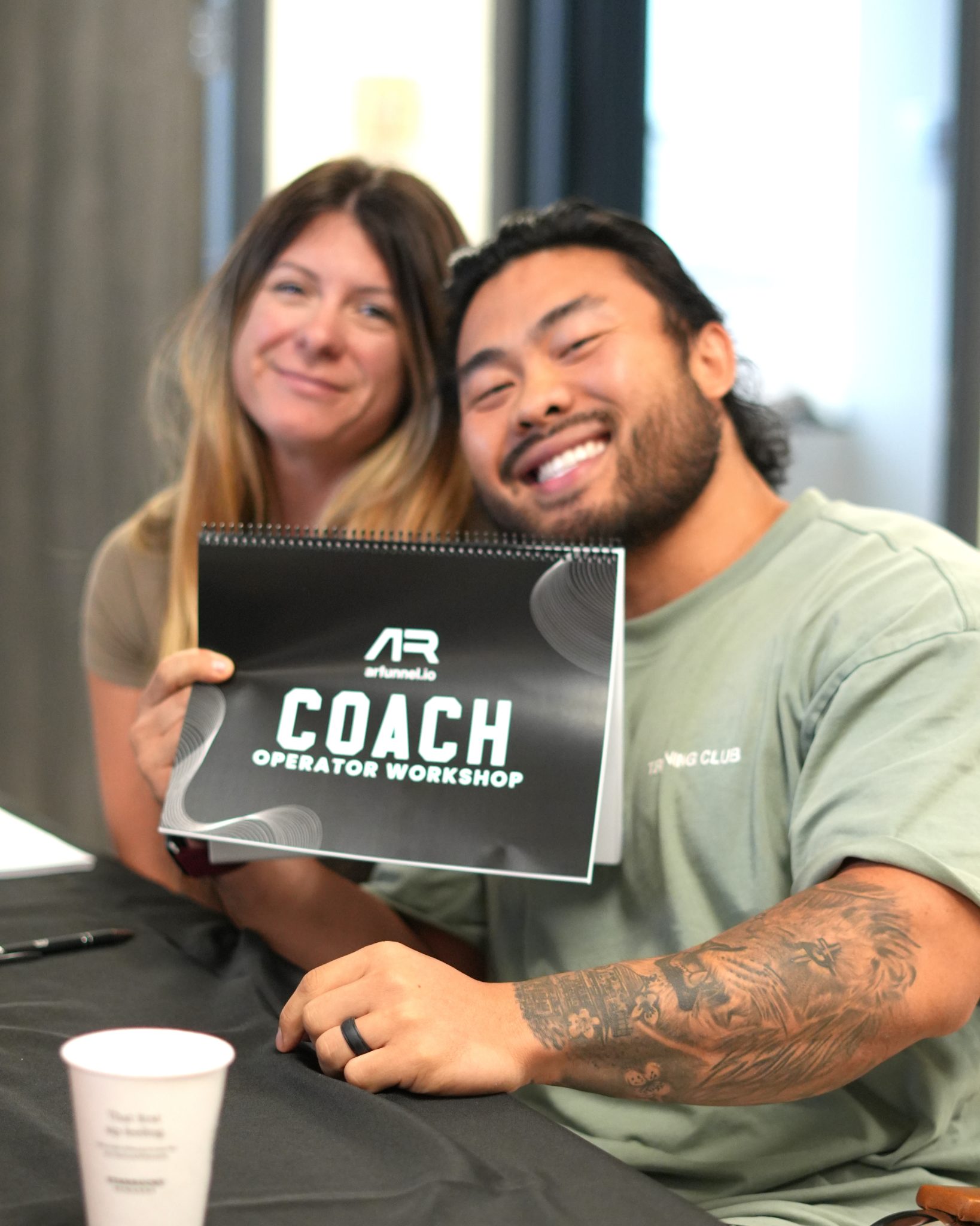 Two attendees smiling and holding a COACH Operator Workshop card