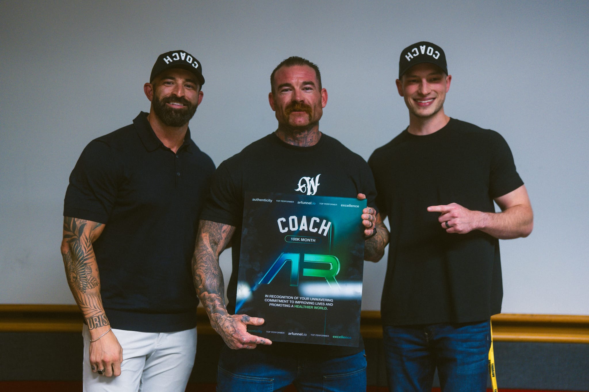 Three coaches holding a COACH AR award plaque